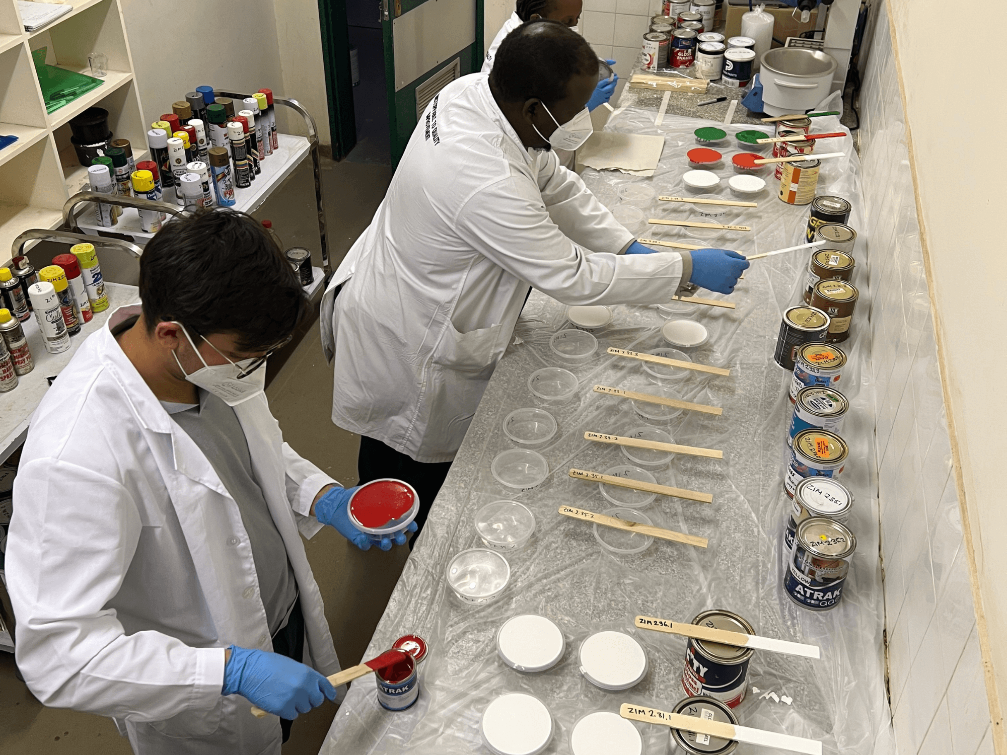 Three people work to test paint samples for lead content as part of the Lead Exposure Elimination Project's work in Zimbabwe.